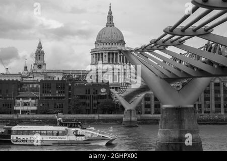 London, Großbritannien - 30. Juli 2021: St Paul's Cathedral und Millennium Footbridge über die Themse, während ein Boot die Brücke überquert. Stockfoto