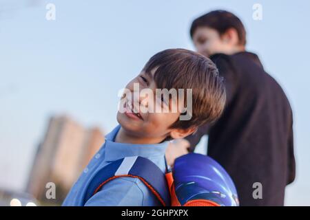 Brüder gehen zur Schule. Der Teenager und sein jüngerer Bruder mit Rucksäcken halten sich die Hände, Brüder lächeln glückliche Gesichter der Kinder. Zurück zur Schule Stockfoto