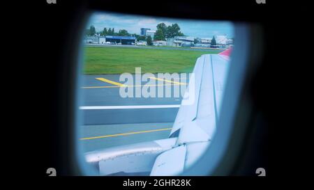 Flügel eines fliegenden Flugzeugs, das auf der Landebahn landet, Blick vom Flugzeugfenster. Ein Passagierflugzeug rollt nach der Landung auf dem Flughafen auf die Start- und Landebahn. Reise- und Luftverkehrskonzept Stockfoto