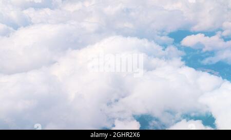 Luftaufnahme von atemberaubenden, flauschigen Wolken, die so weiß wie Schnee am blauen Himmel sind, während der Tagesaufnahme über Spanien. Wolkenlandschaft. Verträumter Hintergrund. Stockfoto