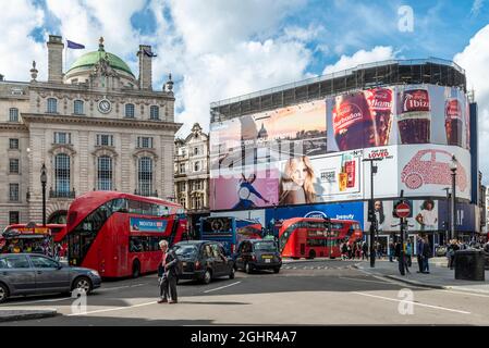 Gebäude mit Werbebannern, Piccadilly Lights, belebte Straße mit roten Bussen, Picadilly Circus, London, England, Vereinigtes Königreich Stockfoto