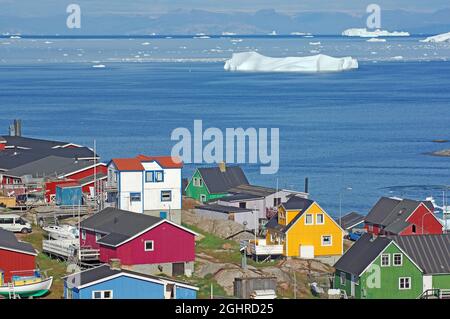 Häuser in verschiedenen Farben, Eisberge in einer Bucht vor der Insel, Arktis, Ilulissat, Disko Bay, Disko Island, Grönland, Dänemark Stockfoto