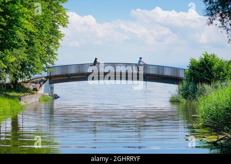 Zwei Radfahrer überqueren die Brücke über den Aach am Zusammenfluss mit dem Bodensee, Arbon im Thurgau, Schweiz Stockfoto