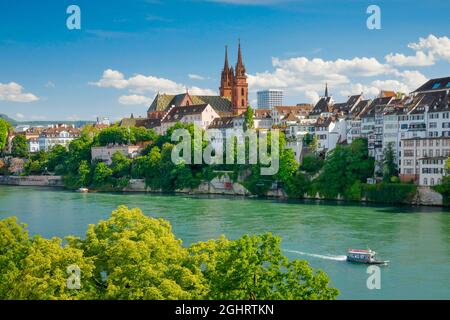 Blick auf den Basler Dom mitten in der Altstadt von Basel mit dem türkisfarbenen Rhein im Vordergrund Stockfoto