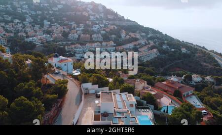 Altea Hills, Spanien 18.08.2021 Stadtbild an der Küste von Altea, Provinz Alicante und Bergen an der Costa Blanca von Spanien. Berge im Hintergrund berühren klaren weißen Himmel. Tagesaufnahme. Stockfoto