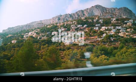 Altea Hills, ein Touristenort in Spanien. Panoramablick. Wunderschöne Ferienvillen auf Hügeln, umgeben von Bäumen. Skyline der Stadt. Malerische Berge vor einem bewölkten Himmel im Hintergrund. Stockfoto