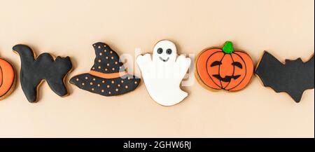 Verschiedene Halloween Lebkuchen - Jack O'Lanterns, Geister, Fledermaus und schwarzer Hut auf beigem Hintergrund. Halloween-Konzept. Draufsicht. Banner Stockfoto