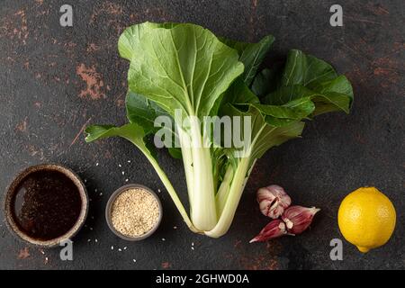 Asiatisches Kochkonzept. Frisch geerntete Bio-Kohl-Choy-chinakohl mit Zutaten auf schwarzem Hintergrund. Draufsicht Stockfoto