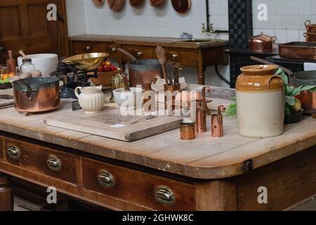 Großer alter Tisch gefüllt mit antiken Kochutensilien und Töpfen aus Steingut in einem alten englischen Landhaus Stockfoto