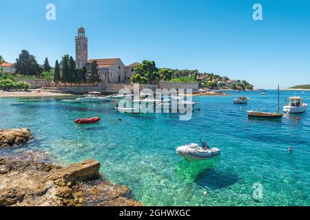 Türkisfarbenes Wasser der Adriatischen Meeresbucht auf der Insel Hvar mit franziskanerkloster und Booten in Dalmatien, Kroatien. Urlaubsziel im Sommer Stockfoto