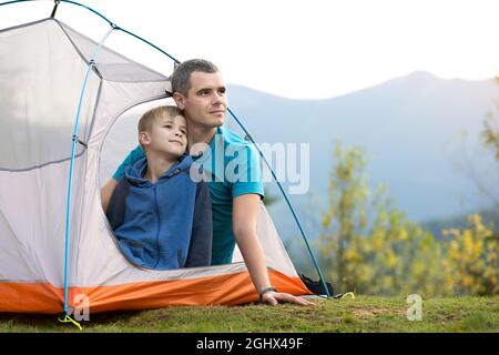 Vater mit seinem Kind Sohn zusammen in einem Zelt in den Sommerbergen ruhen. Aktives Familienrekreationskonzept. Stockfoto