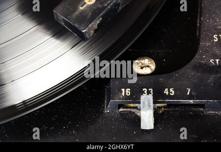 Schwarze Vinyl-Schallplatten drehen sich auf dem Drehteller, wobei der Geschwindigkeitsregler auf 33 U/min eingestellt ist. Alte Audiogeräte. Vinyl-Plattenspieler Stockfoto