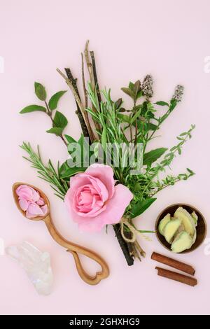 Zutaten für den magischen Liebestrank mit Kräutern und Rosenblüten, gebunden in einem Hexenbündel mit Ingwer- und Zimtgewürz, Quarzkristall und Liebeslöffel Stockfoto