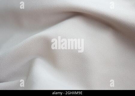 Nahaufnahme Struktur aus beigem Stoff oder Stoff in beiger Farbe. Stoff Textur beige Hintergrund. Zerknittert beige Stoff Stockfoto