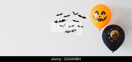 Fröhliches Halloween Banner mit Fledermäusen und Luftballons an der weißen Wand. Minimalistischer Style. Halloween Hintergrund. Stockfoto