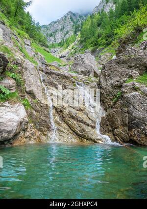 Kleiner Wasserfall mit dem Wasser, das durch den Felsen in einem natürlichen Pool mit türkisfarbener Farbe fließt Stockfoto