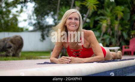 Gesunde Ältere Frau, Die Auf Dem Boden Am Pool Liegt Stockfoto