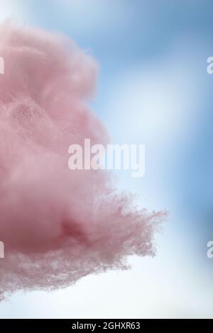 Rosa Zuckerwatte auf einem Stock, der gegen den Himmel gehalten wird, um wie eine Wolke auszusehen. Stockfoto