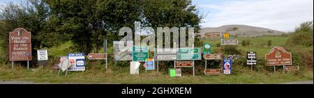 Mehrere Straßen-, Richtungs- und Werbeschilder auf der N67 im Burren, County Clare, Irland. Stockfoto