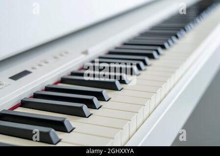 Digitales Klavier, das über die Tasten schaut. Geringe Schärfentiefe. Klassische Musik auf elektronischem Digitalpiano. Schöne Klaviertasten aus nächster Nähe. Stockfoto