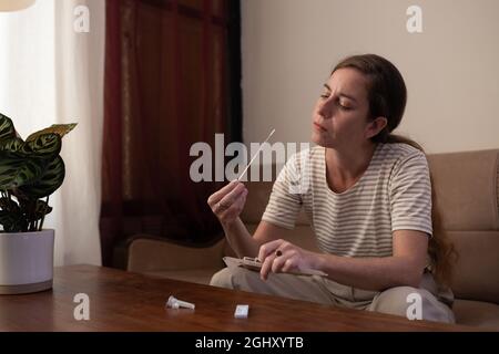 Frau führt zu Hause einen Covid-19-Selbsttest durch Stockfoto