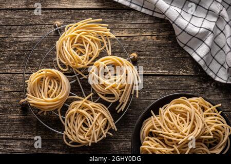 Italienisches Pastanest. Ungekochte Spaghetti nisten auf einem alten Holztisch. Draufsicht. Stockfoto