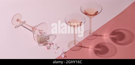 Minimalistischer Schuss Rosenwein in zwei Cocktail-Roségläsern, verziert mit Rosenhortenblüten auf weißem und rosafarbenem Hintergrund Stockfoto