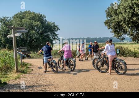 Urlauber erkunden die Nordküste Norfolks mit gemieteten Rad Power E-Bikes. Wir hielten an einem Wegweiser in Holkham. Stockfoto