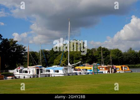 Die Boote vertäuten auf Malthouse Broad am Kai von Ranworth, Norfolk, England, bei Sonnenschein, aber mit bedrohlichen Wolken darüber Stockfoto