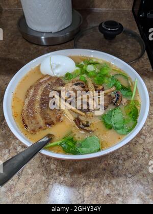 Blick von oben auf den hausgemachten Schweinekaschu Ramen, serviert mit einem weich gekochten Ei, grünen Zwiebeln, Pilzen und Spinat Stockfoto