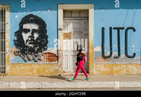 Eine Frau geht an einem Bild von Che Guevara in Trinidad, Kuba, vorbei. Stockfoto