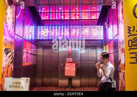 In der Dämmerung in Hongkong steht ein Mann an der Nathan Road an der Seite der Straße. Stockfoto