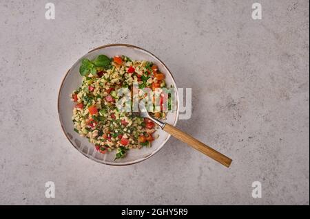 Salat aus Tabbouleh. Traditionelles nahöstliches oder arabisches Gericht mit Petersilie, Minze, Bulgur, Tomaten in einer Schüssel mit Gabel. Draufsicht. Speicherplatz kopieren Stockfoto