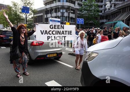 Zwei Demonstranten gehen zwischen dem Verkehr mit einem Transparent mit der Aufschrift: ‘KEINE IMPFPFLICHT', vor dem Eingang des neuen temporären Parlamentsgebäudes; während die Demonstranten niederländische Parlamentarier nach ihrer Rückkehr aus einer Sommerpause willkommen heißen. Einige hundert Demonstranten versammelten sich heute Morgen vor dem neuen niederländischen parlamentsgebäude und demonstrierten gegen Koronamaßnahmen und das, was sie als diktatorische Regierung betrachten. Das Gebäude ist ein vorübergehendes Zuhause, da die Renovierung des Binnenhofs den Sitz der niederländischen Regierung länger als 5.5 Jahre in Anspruch nehmen wird. (Foto von Charles M Vella/SOPA Images/ Stockfoto