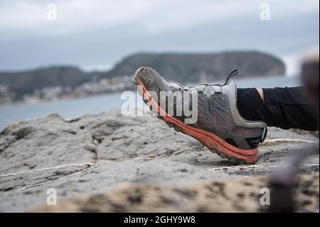 Fuß in Trekkingschuh auf den Felsen mit unfokussierten Hintergrund. Porträt Stockfoto