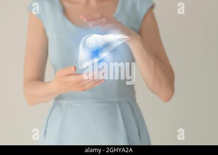 Nicht erkennbare weibliche Patientin in blauer Kleidung, hervorgehobene handgezeichnete Leber in den Händen. Menschliches Verdauungssystem Fragen Konzept. Stockfoto