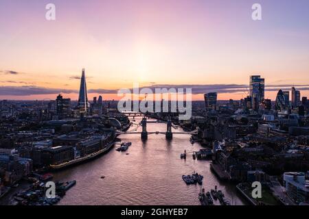 Drone Blick auf die berühmte Tower Bridge über dem Ozean umgeben von Gebäuden und Wolkenkratzern unter einer bewölkten Dämmerung und Dämmerung Morgen Stockfoto