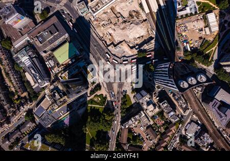 Blick aus der Vogelperspektive auf hohe Finanz- und Geschäftsgebäude mit Schatten und Autos, die sich an einem hellen, sonnigen Tag in der Londoner Stadt auf der Stadtstraße bewegen Stockfoto