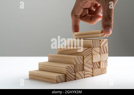 Holzblock, der von Hand als Treppenstufe stapelt, anordnen Stockfoto