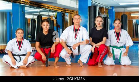 Selbstbewusste Frauen in Kimonos mit Kampfsporttrainer im Fitnessstudio Stockfoto
