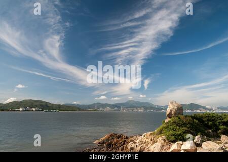 Blauer Himmel mit Zirruswolken über den Brücken Tsing Ma und Ting Kau, von Peng Chau aus gesehen, einer abgelegenen Insel Hongkongs Stockfoto