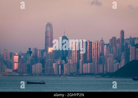 Die untergehende Sonne spiegelte sich in Hochhäusern auf Hong Kong Island wider, mit einem rosafarbenen Himmel im Osten aufgrund des Phänomens „Gürtel der Venus“ Stockfoto