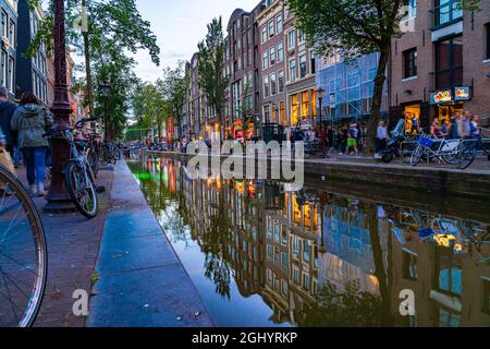 Amsterdam, Holland - 17. August 2017; Geschäfte und Geschäfte im Rotlichtviertel spiegeln sich in einem ruhigen Kanal wider, der in der Dämmerung aufgenommen wurde, wobei die Langzeitbelichtung verschwimmt Stockfoto