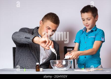 Konzept der chemischen aus- und Weiterbildung. Nahaufnahme eines Jungen und seines Vaters, die ein heimisches Experiment machten, Schleim aus Klebstoff, Natriumtetraborat A machten Stockfoto