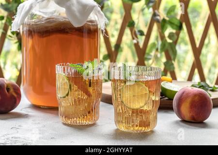 Kombucha-Tee leicht alkoholisches, leicht brausendes Getränk mit Pfirsich und Limette. Hausgemachte Gärung. Probiotisches, gut gesundes Getränk. Stockfoto