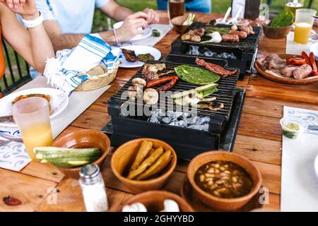 lateinische Menschen, die mexikanisches Essen, Tacos, würzige Salsa, Tortillas, Bier, Snacks und Menschen überreichen Holztisch auf einer Restaurantterrasse in Mexico Lati Stockfoto