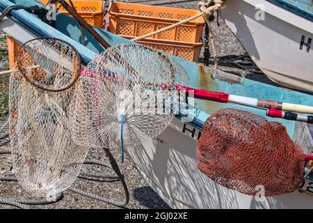 Drei kommerzielle Landungsnetze, die für die Fischerei verwendet werden, ruhen auf einem blau-weißen Boot Stockfoto