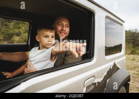 Vater lehrt den kleinen Sohn auf einer Autoreise zu fahren Stockfoto