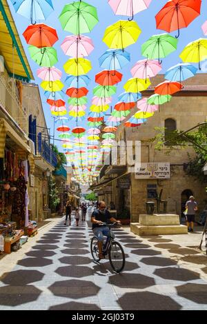 Jerusalem, Israel - 30. August 2021: Fußgänger und bunte Regenschirme (Sonnenschirme), in der Yoel Moshe Solomon Street, dem historischen Nachalat Shiva Nachbarn Stockfoto