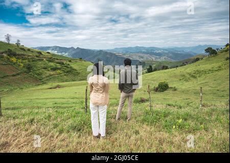 Junges asiatisches Paar, das im Urlaub auf dem Weidehang auf dem Land steht Stockfoto
